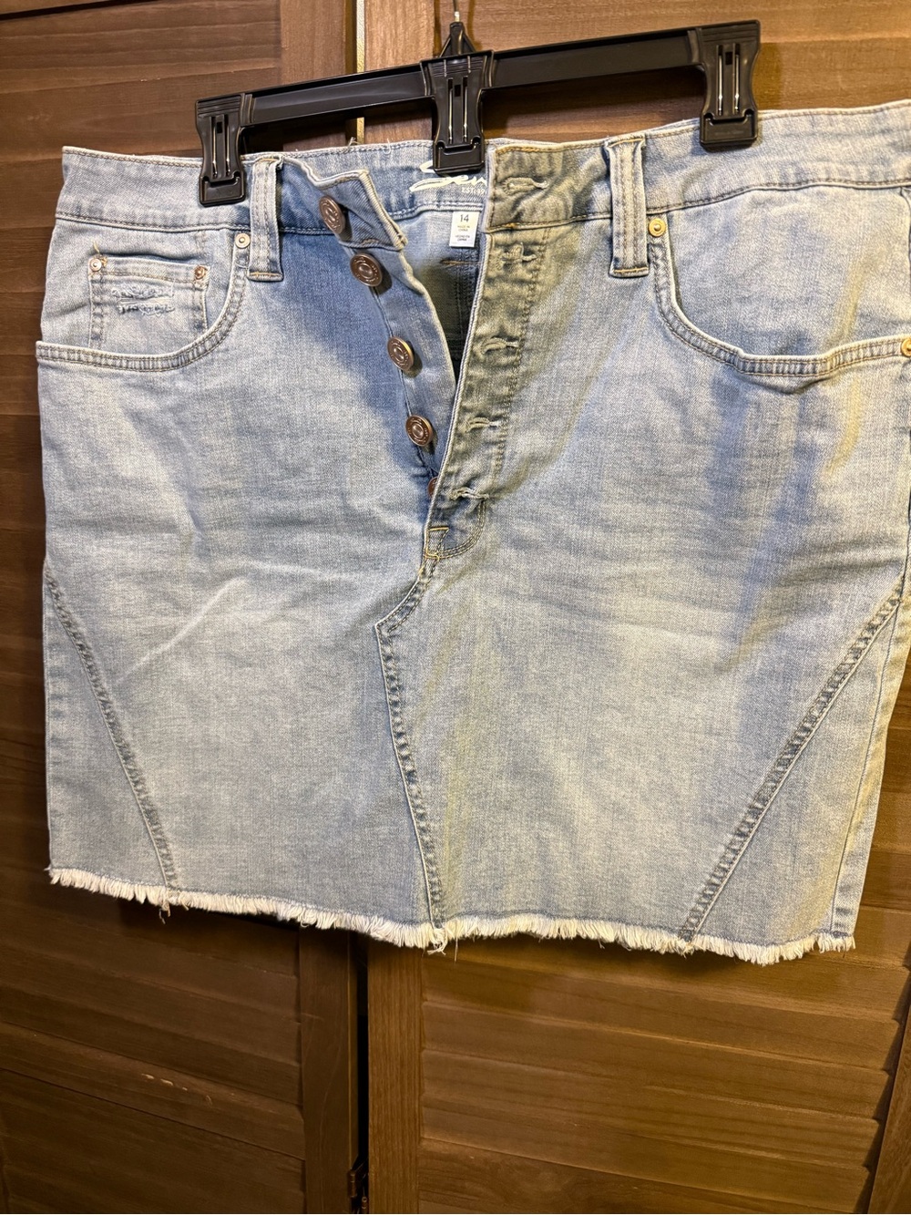 Light wash, distressed denim skirt with bottom, fringe, and exposed button fly